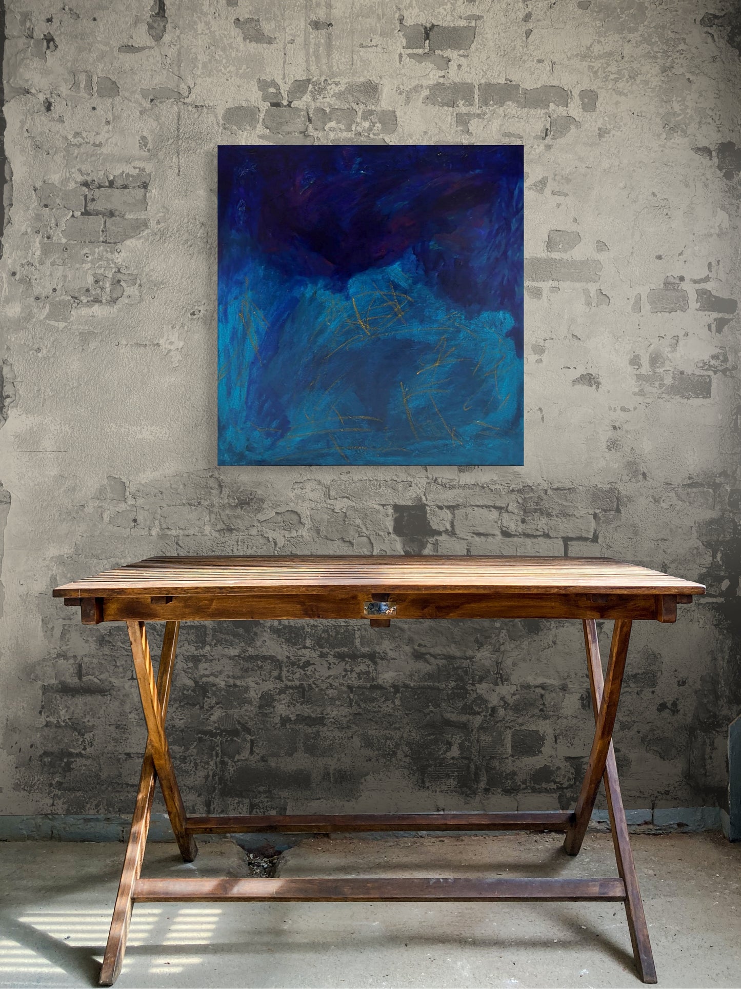 Wooden table against a textured wall with a blue abstract painting