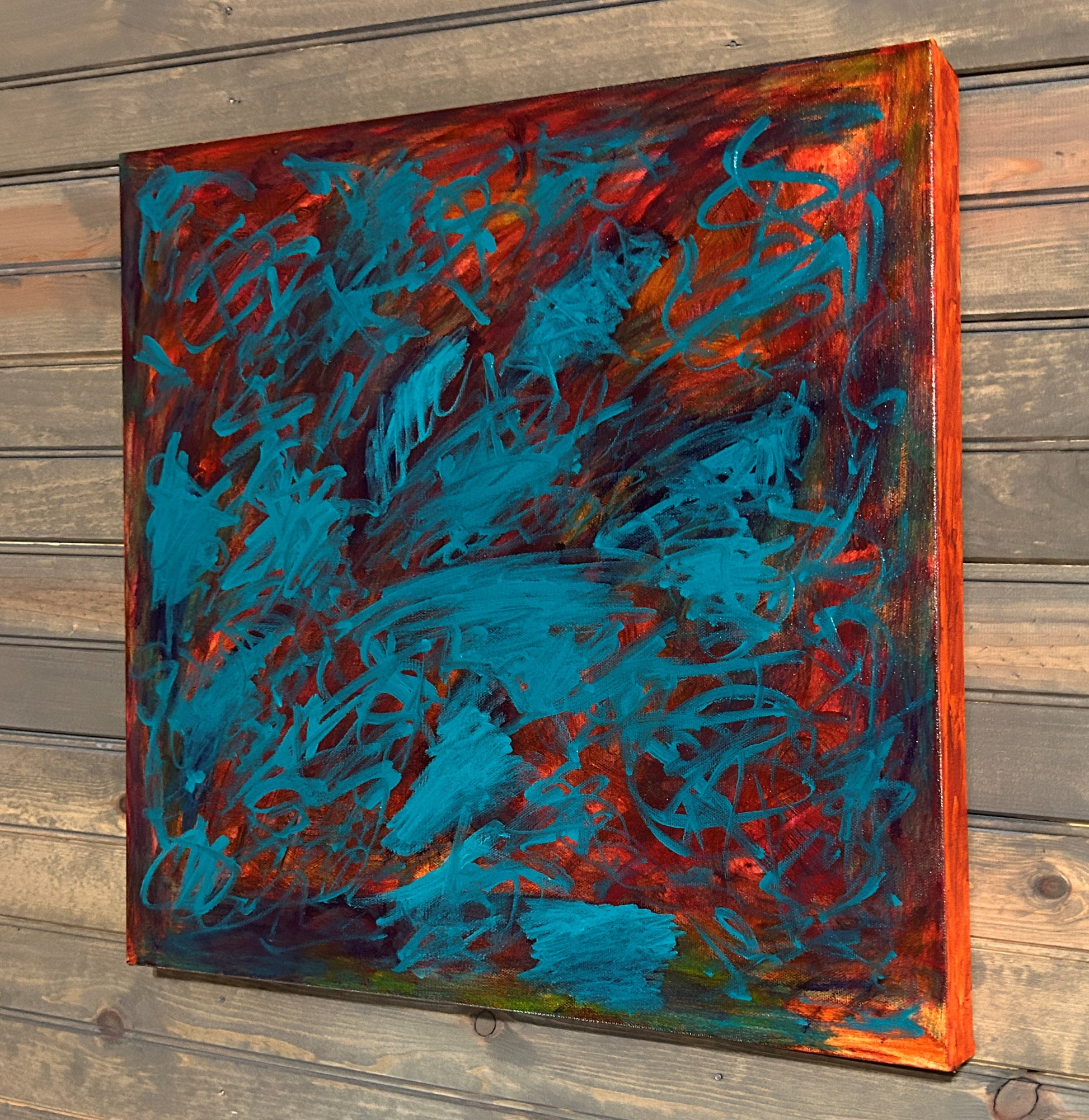 Abstract painting with blue and red strokes on a wooden surface
