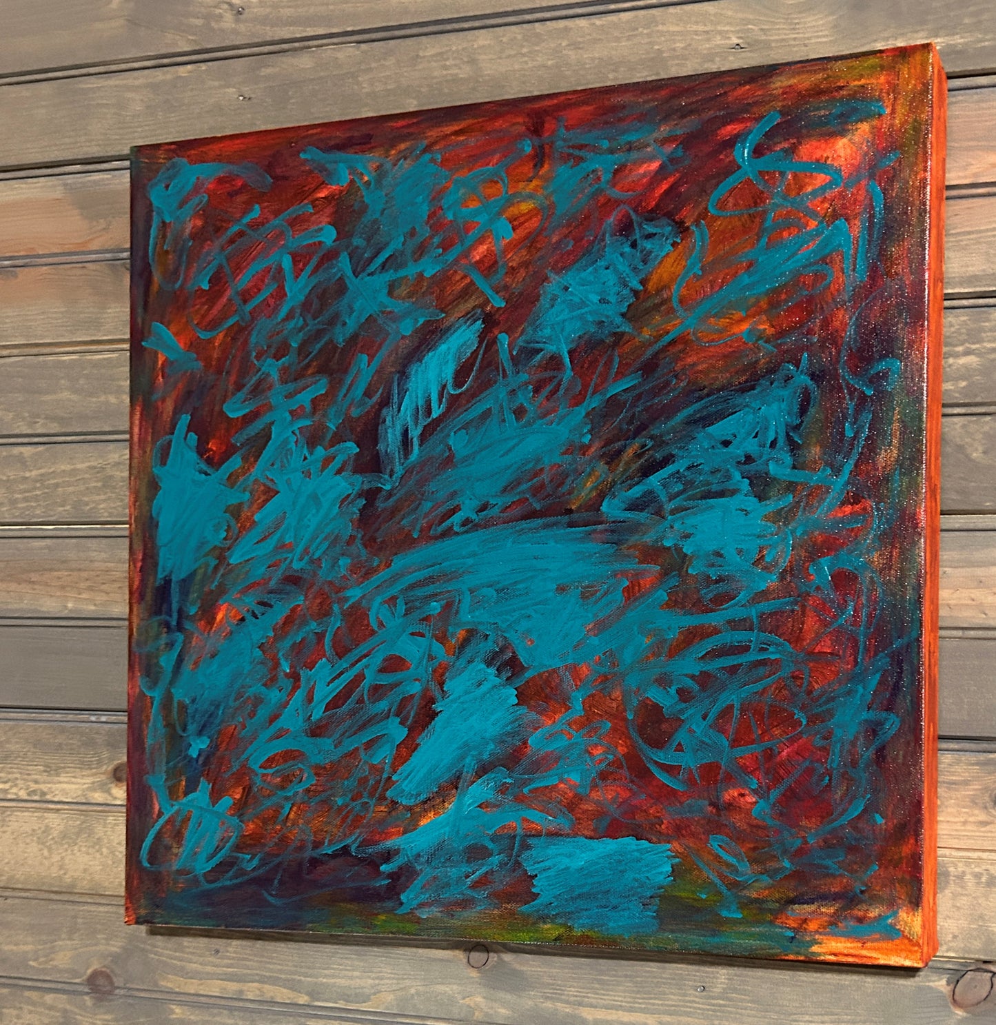 Abstract painting with blue and red strokes on a wooden surface