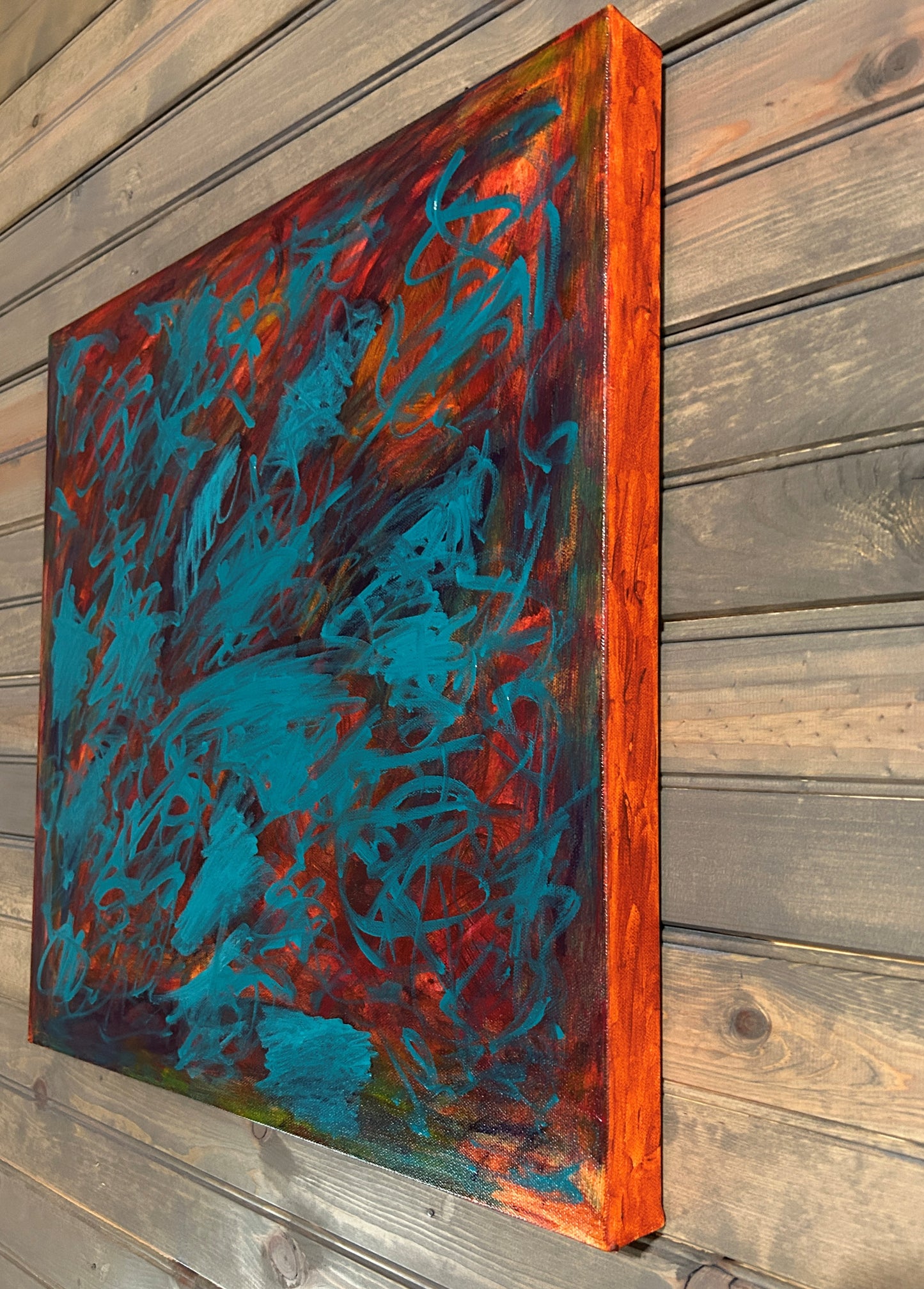 Abstract painting with blue and red hues on a wooden panel